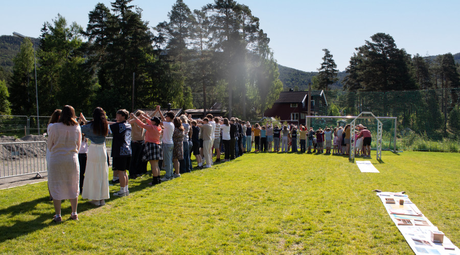 Elever og lærere skaper menneskeskapt bru med latter, smil og sang
