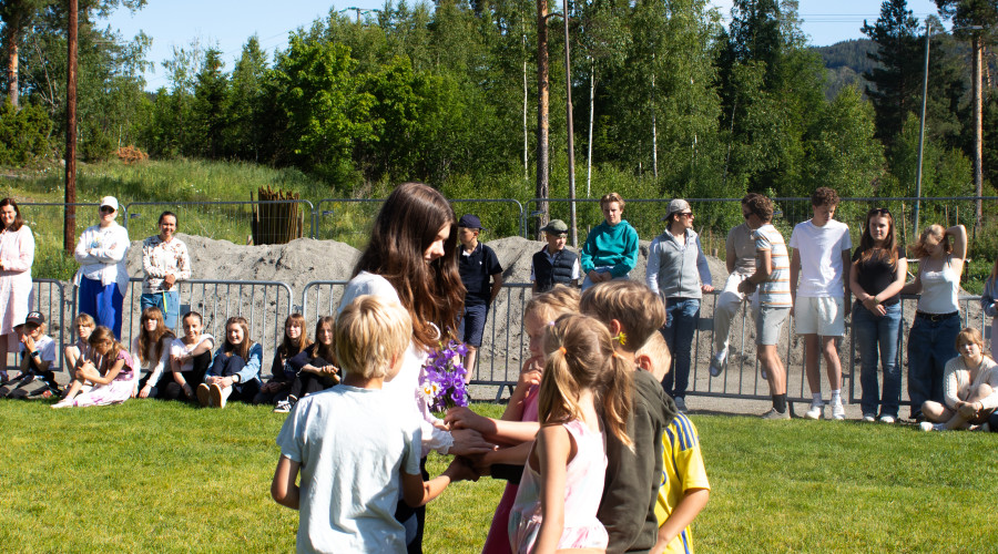 Yngre elever gir blomster til de eldste elevene under portalseremoni